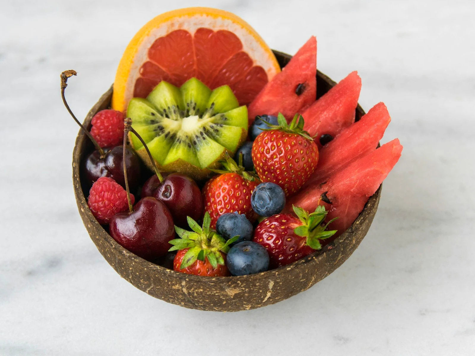 Fruit mix made with chopped pieces of red and green apples, mandarin orange segments, fresh strawberry slices, and blueberries.