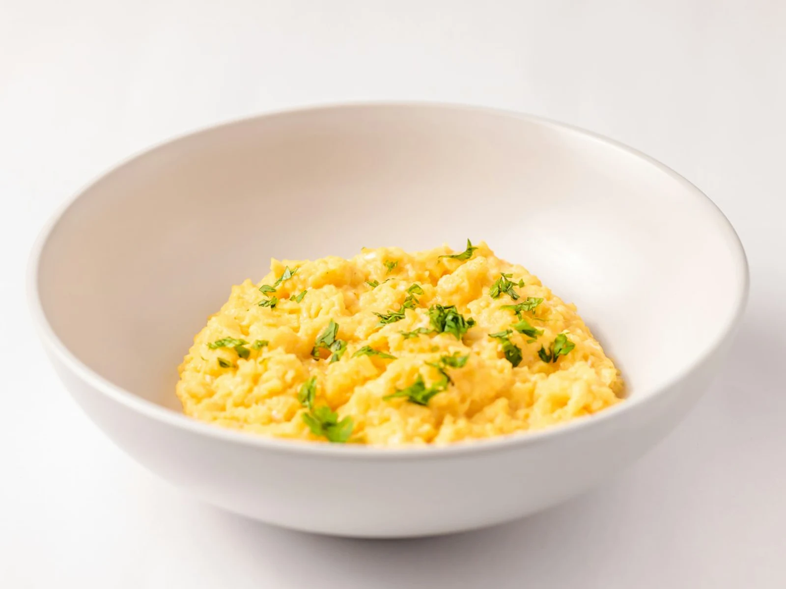 A plate of scrambled eggs with cheese, chicken strips, and hash brown rounds, accompanied by a small cup dipping sauce.